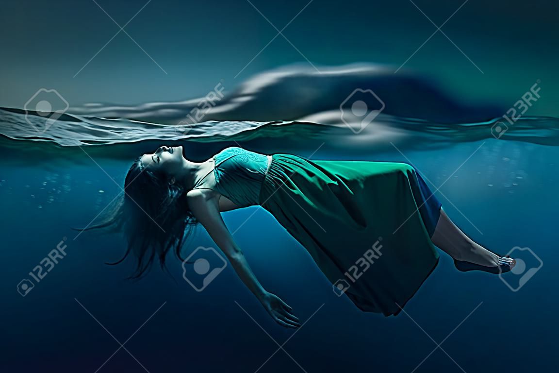 Mulher que flutua debaixo d'água