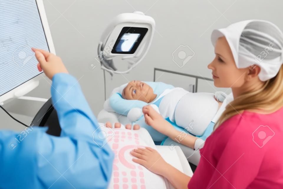 병원에서 임신 한 여자를 검사하는 동안 초음파 모니터를보고 산부인과
