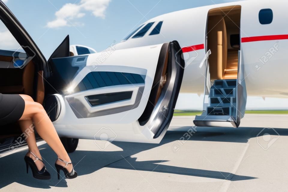 Низкий раздел богатая женщина выходя из автомобиля, припаркованного перед частном самолете