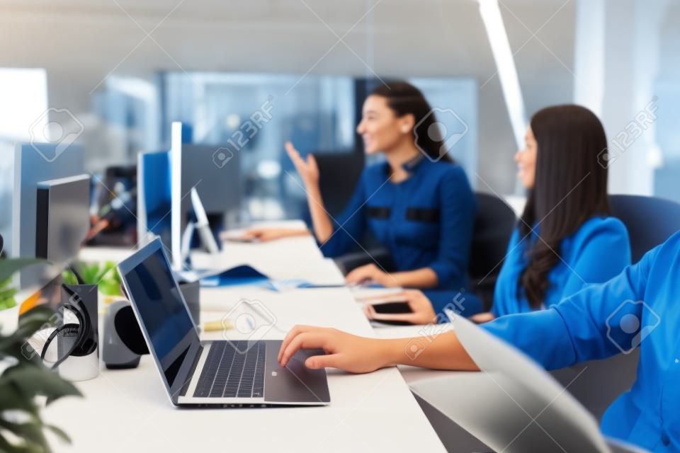 젊은 동료 팀은 밝은 현대식 사무실에서 노트북과 문서가 있는 책상에 앉아 일합니다.