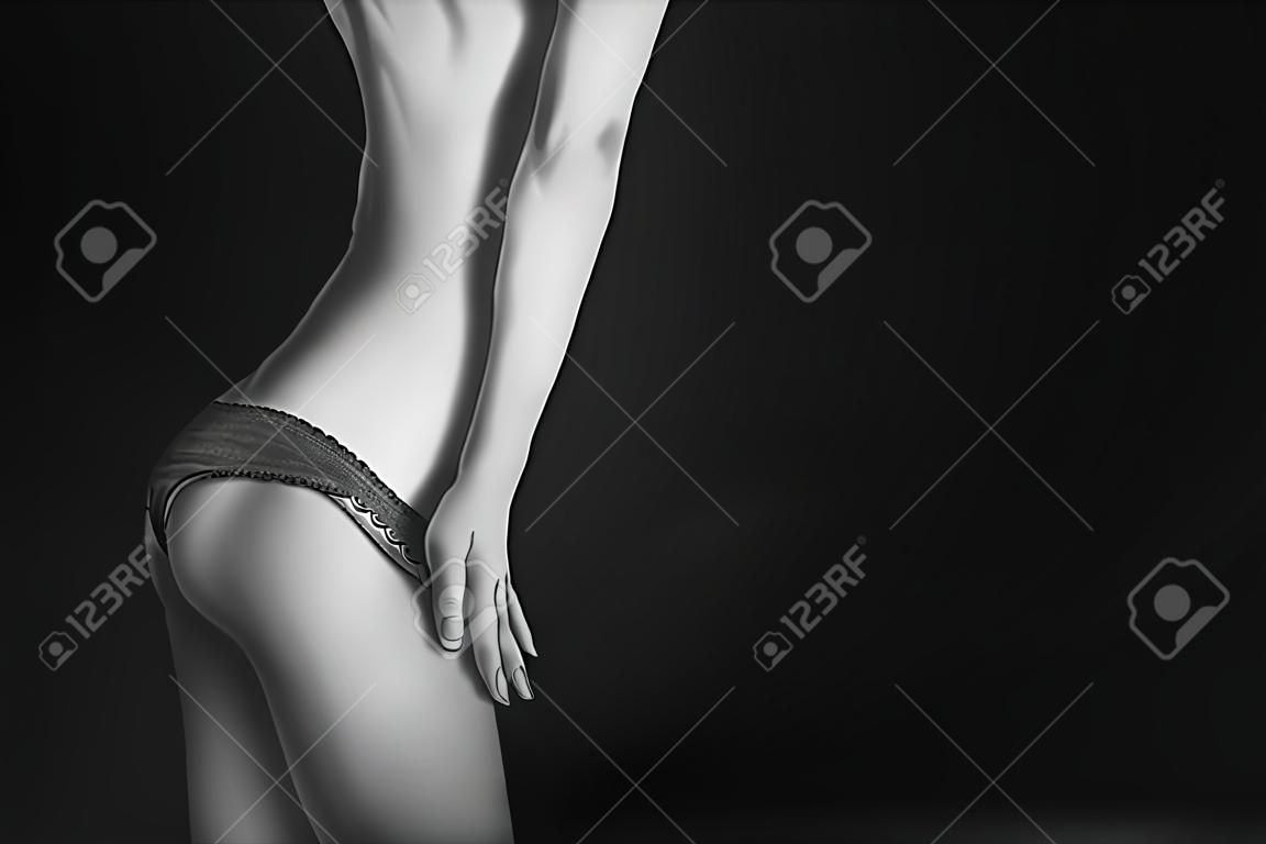 déshabiller culotte de tan corps féminin mince sur fond noir avec fond, monochrome