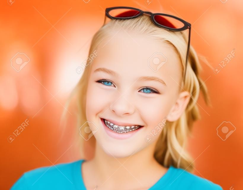 bella ragazza teenager bionda con le parentesi graffe sui suoi denti che sorride