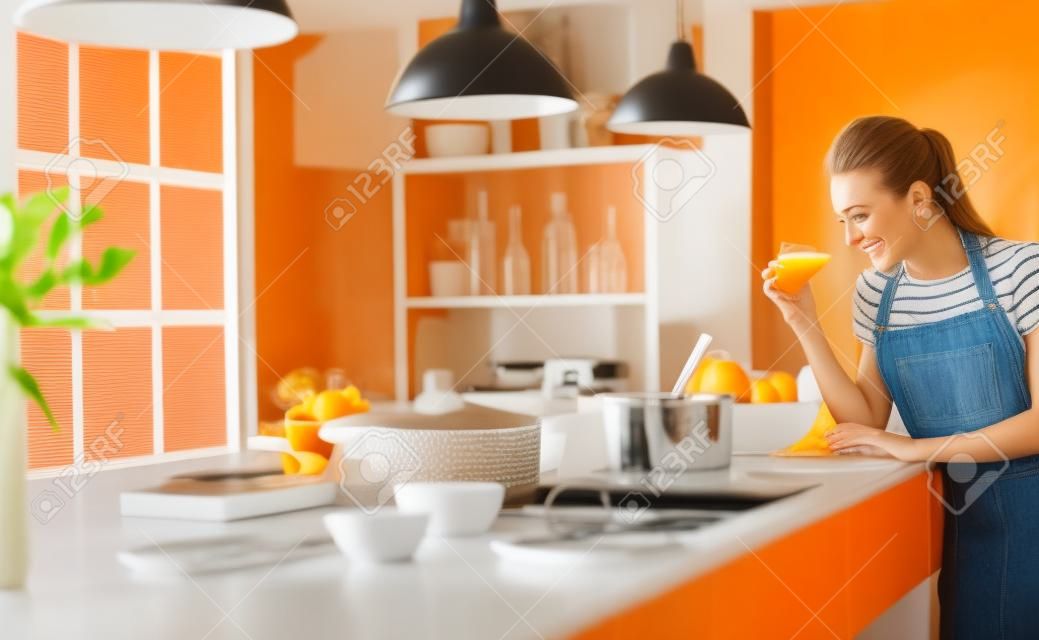 Attraktive Frau, die ein Glas Orangensaft hält, während sie in der Küche steht