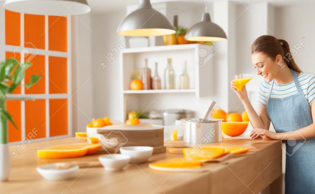 Attraktive Frau, die ein Glas Orangensaft hält, während sie in der Küche steht