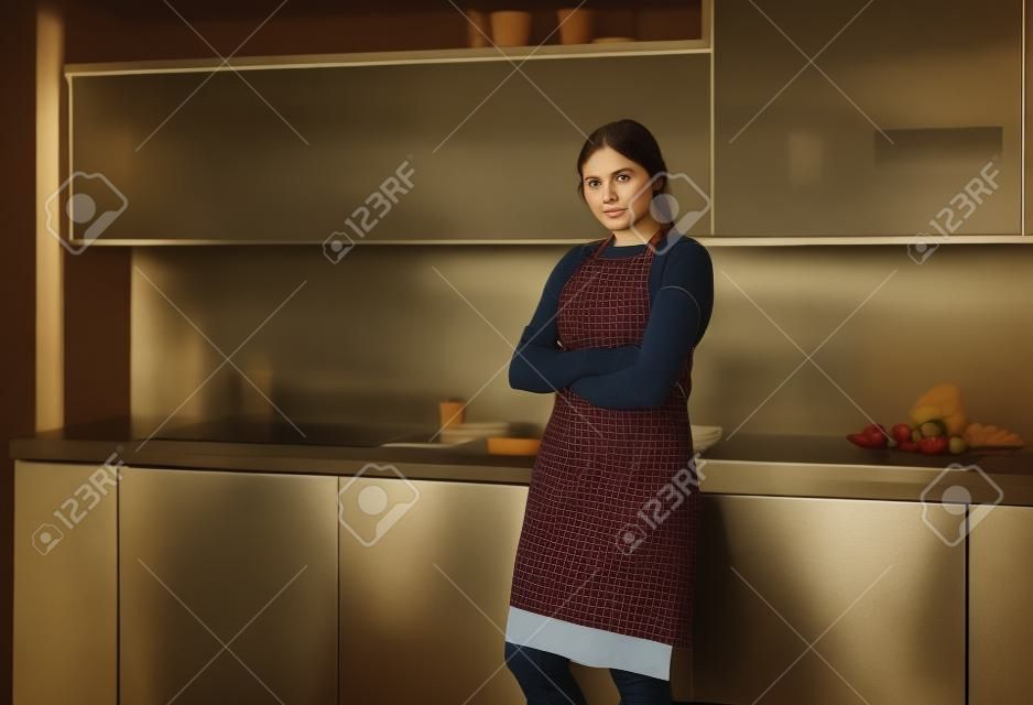 retrato, de, mujer joven, posición, con, armamentos cruzaron, contra, cocina, plano de fondo