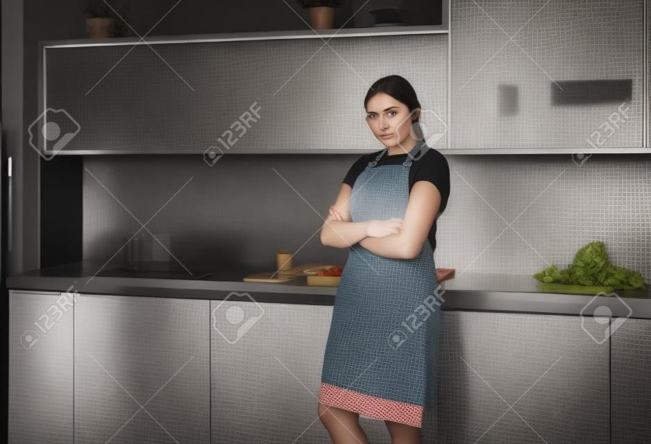 retrato, de, mujer joven, posición, con, armamentos cruzaron, contra, cocina, plano de fondo