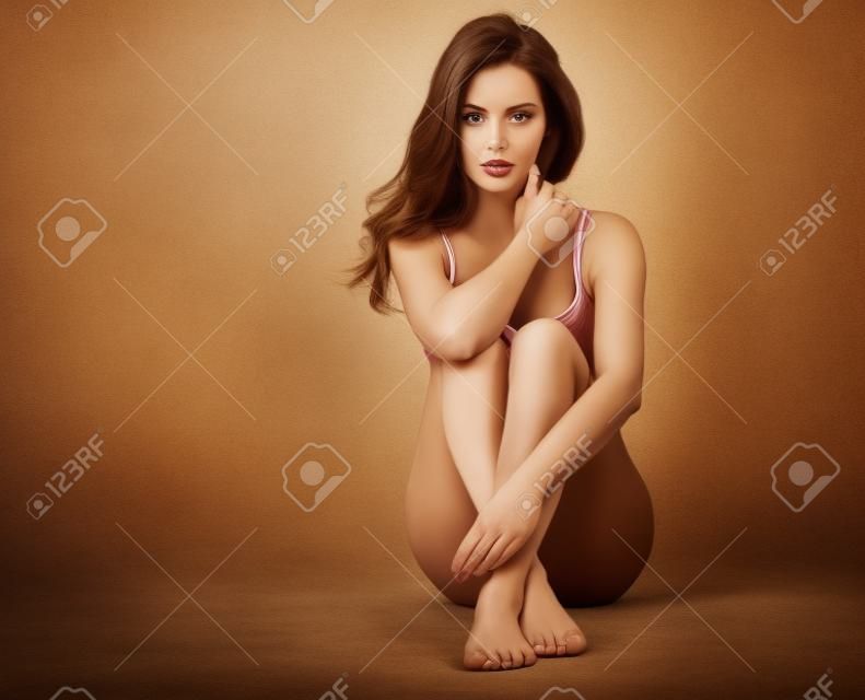 Mujer descalza hermosa que se sienta en el suelo.