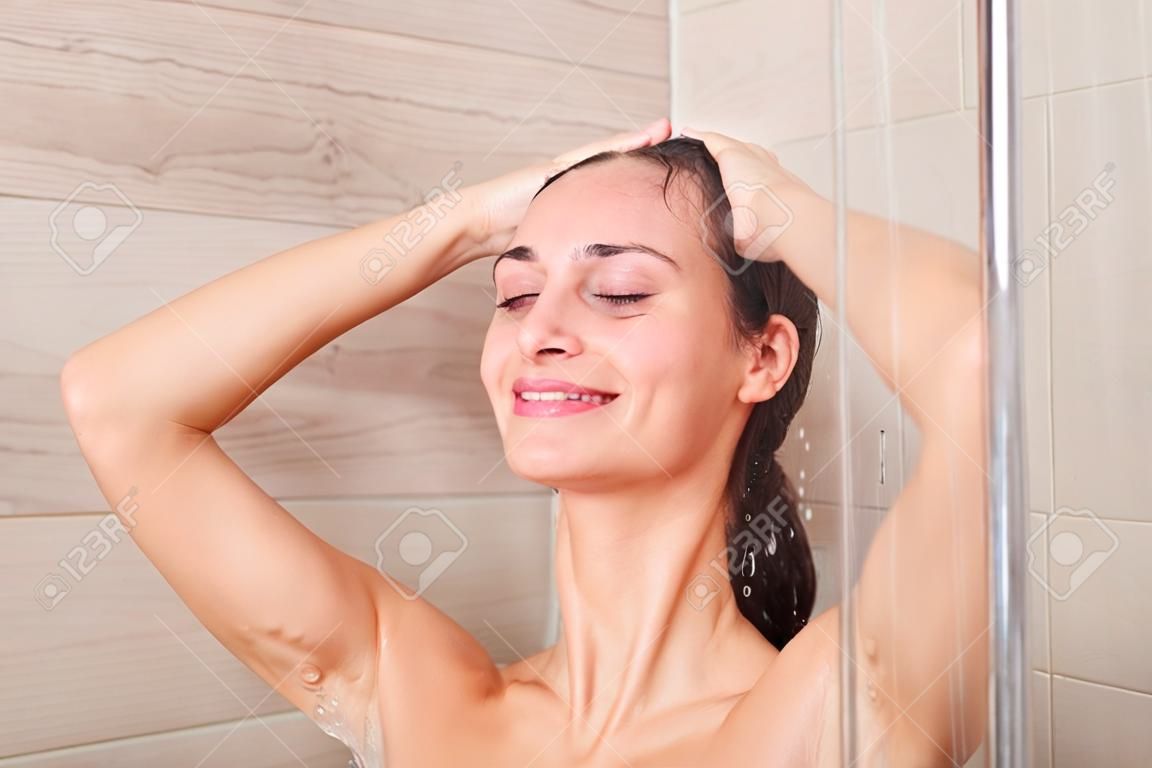 Giovane donna seducente sotto la doccia in bagno