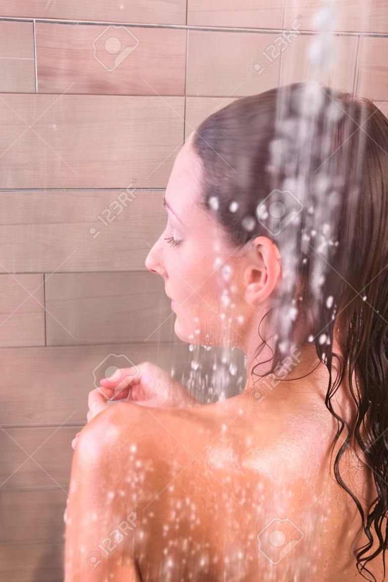 Young beautyful woman under shower in bathroom