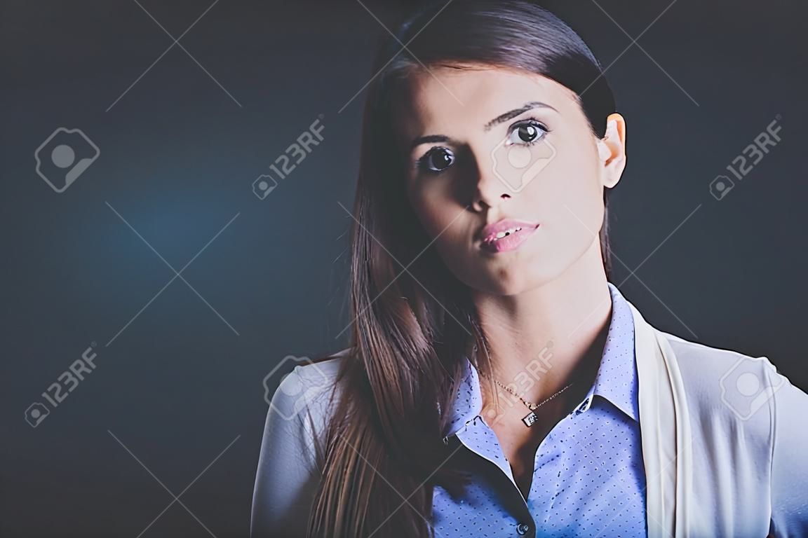 Porträt einer Geschäftsfrau , gegen dunklem Hintergrund . Frau lächelnd . Porträt einer Frau