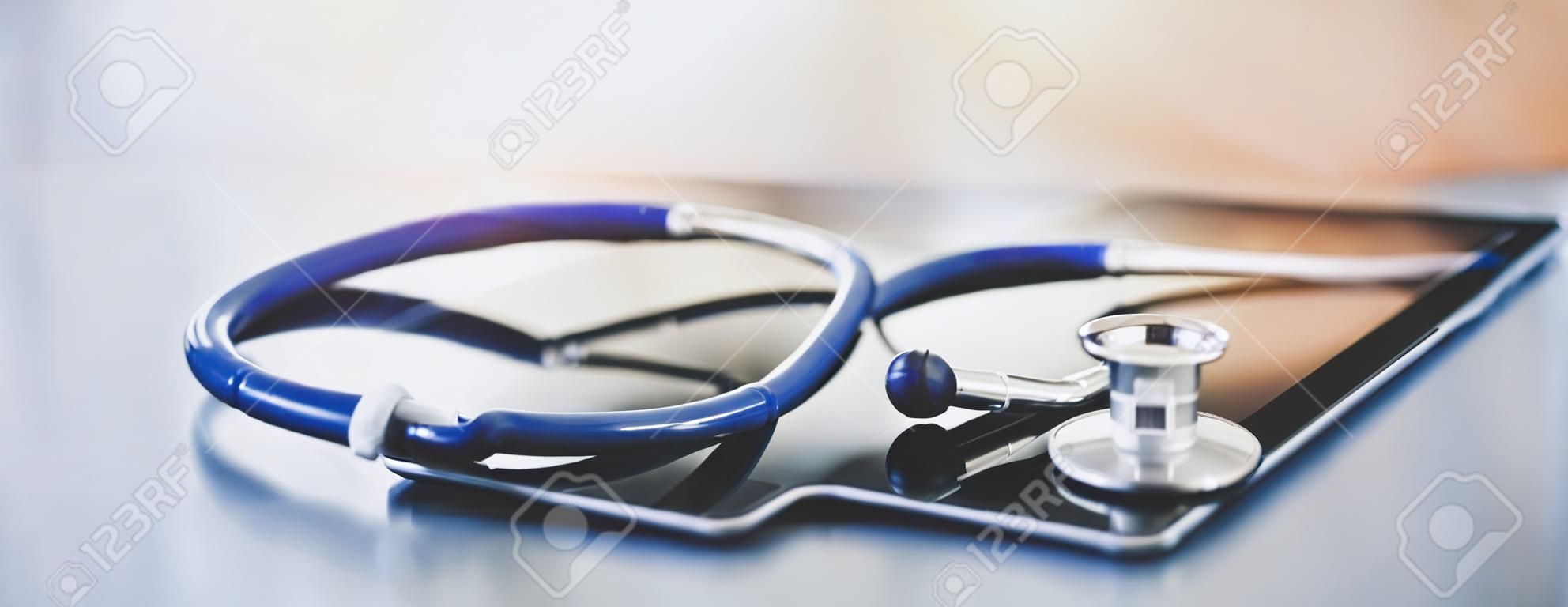 Medizinische Geräte: blaues Stethoskop und Tablet auf weißem Hintergrund.