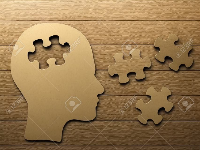 Concepto de cerebro cabeza de rompecabezas. Perfil de la cabeza humana hecho de papel marrón con una pieza de rompecabezas recortada. Elige la personalidad que más te convenga