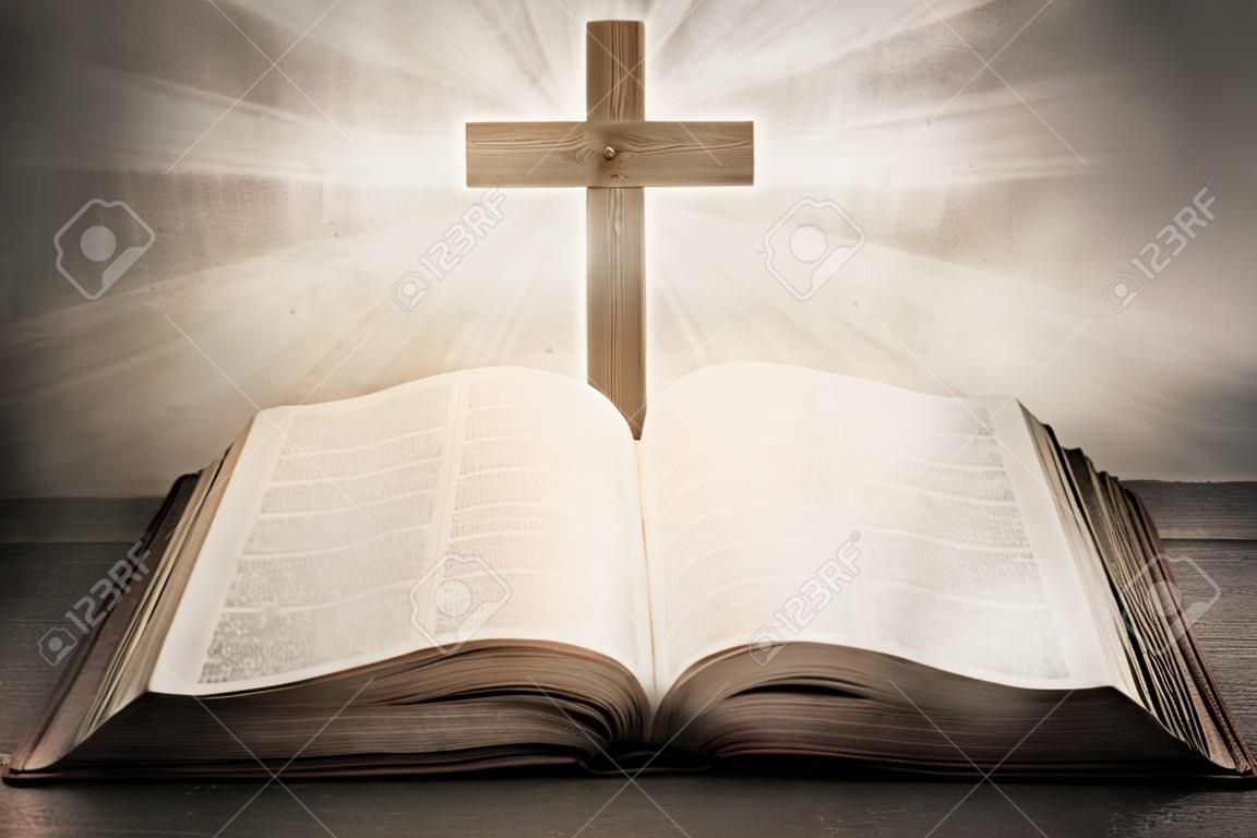 Открытая Библия с деревянным крестом в середине. Христианская концепция