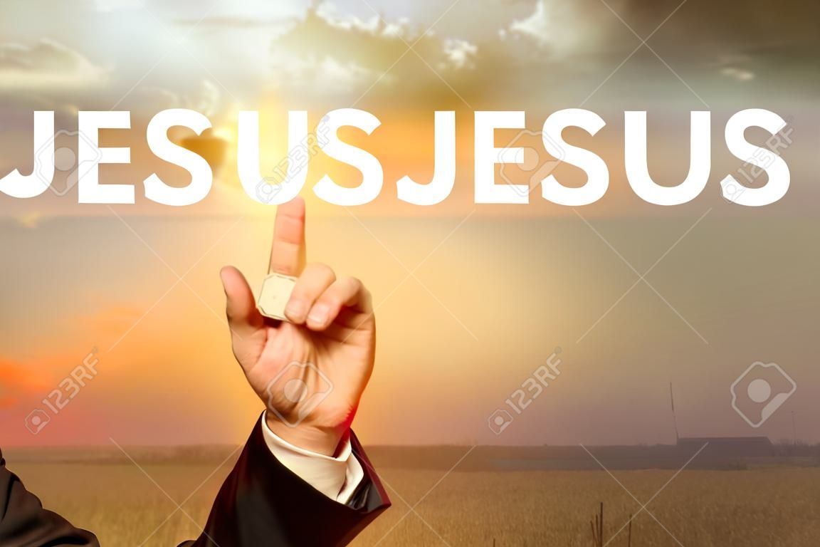 Businessman hand showing Jesus text with a sunrise sky background