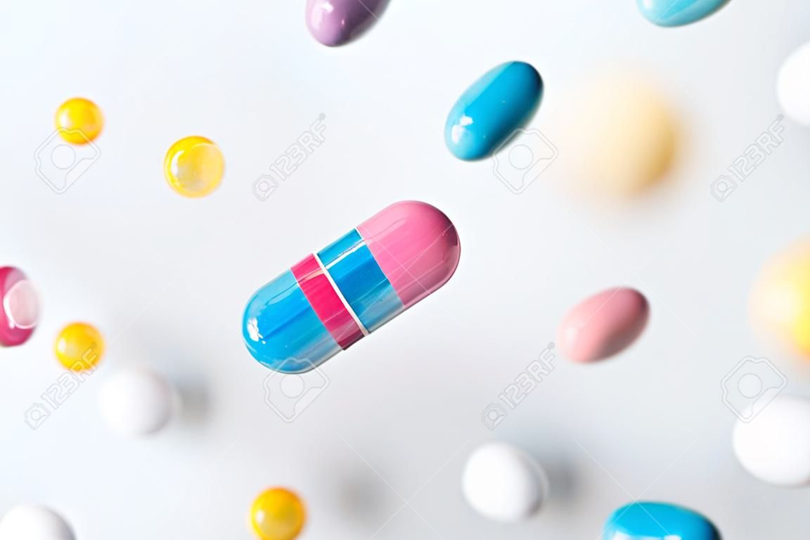 Colorful pills flying above white background, levitation effect.