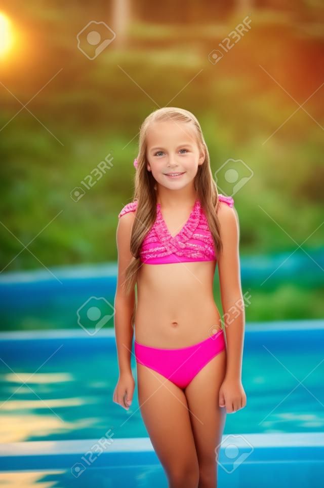 Meisje in een badpak in de zomer. Zonsondergang. Meisje 9 jaar oud. Tiener 10 jaar oud. Het schoolmeisje was zwemmen in het zwembad. Zwembad in het bos of in de frisse lucht. Portret van een meisje van 9 jaar oud. Zomer's binnenkort