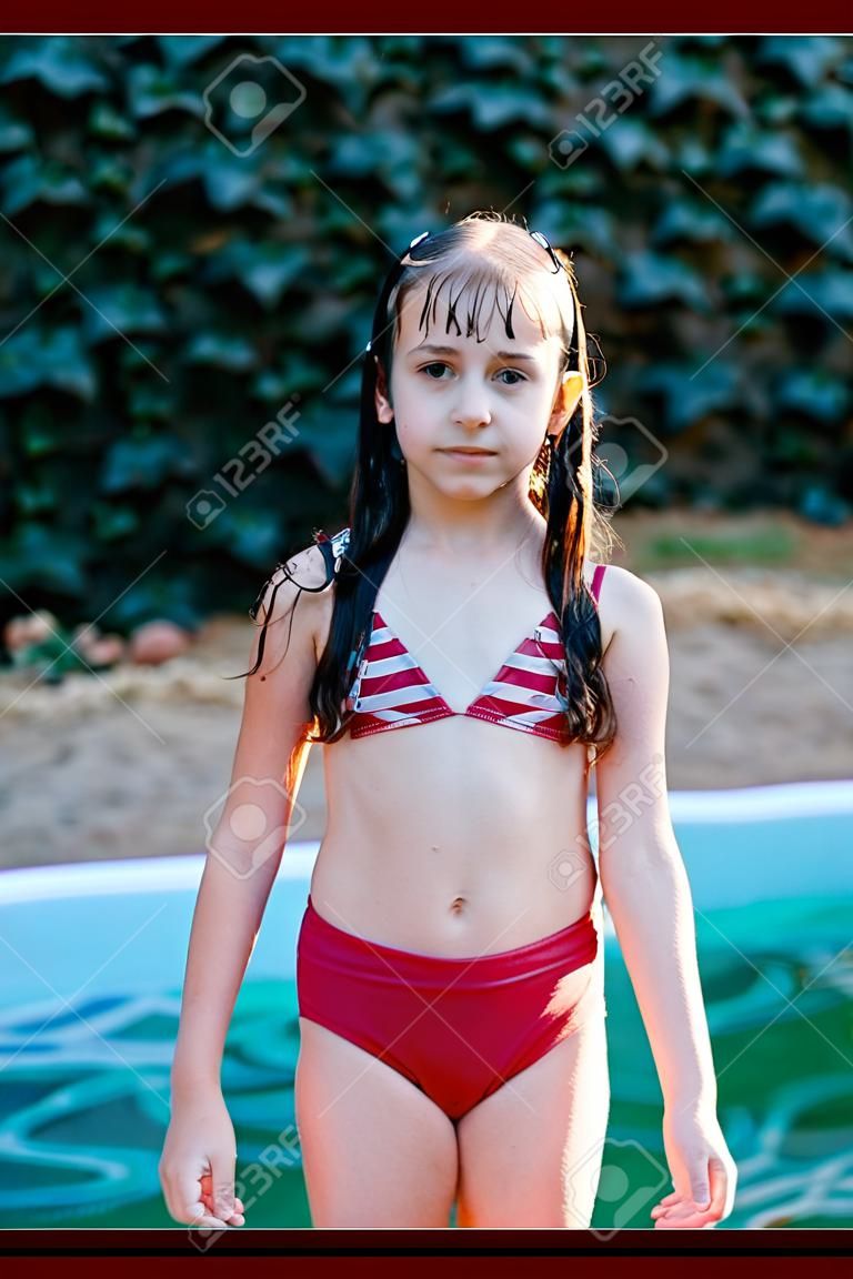Mädchen im Badeanzug im Sommer. Sonnenuntergang. Mädchen 9 Jahre alt. Teenager 10 Jahre alt. Das Schulmädchen schwamm im Pool. Pool im Wald oder an der frischen Luft. Porträt eines Mädchens von 9 Jahren. Bald ist Sommer