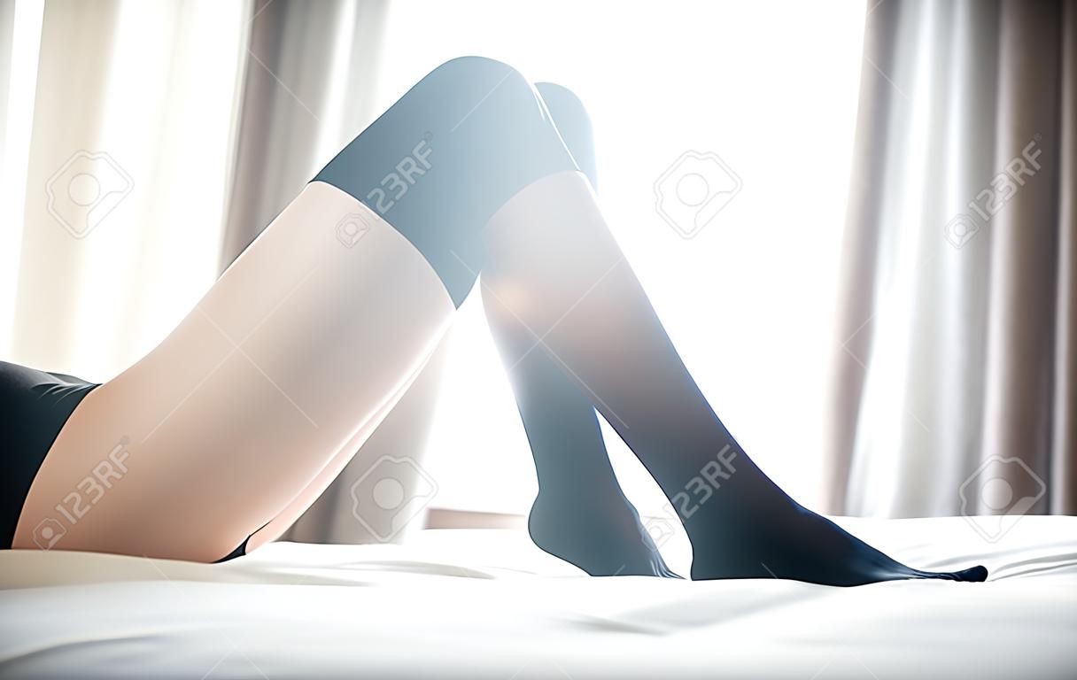 Schöne schlanke Frau in schwarzen Höschen und Kniestrümpfe auf dem Bett zu Hause