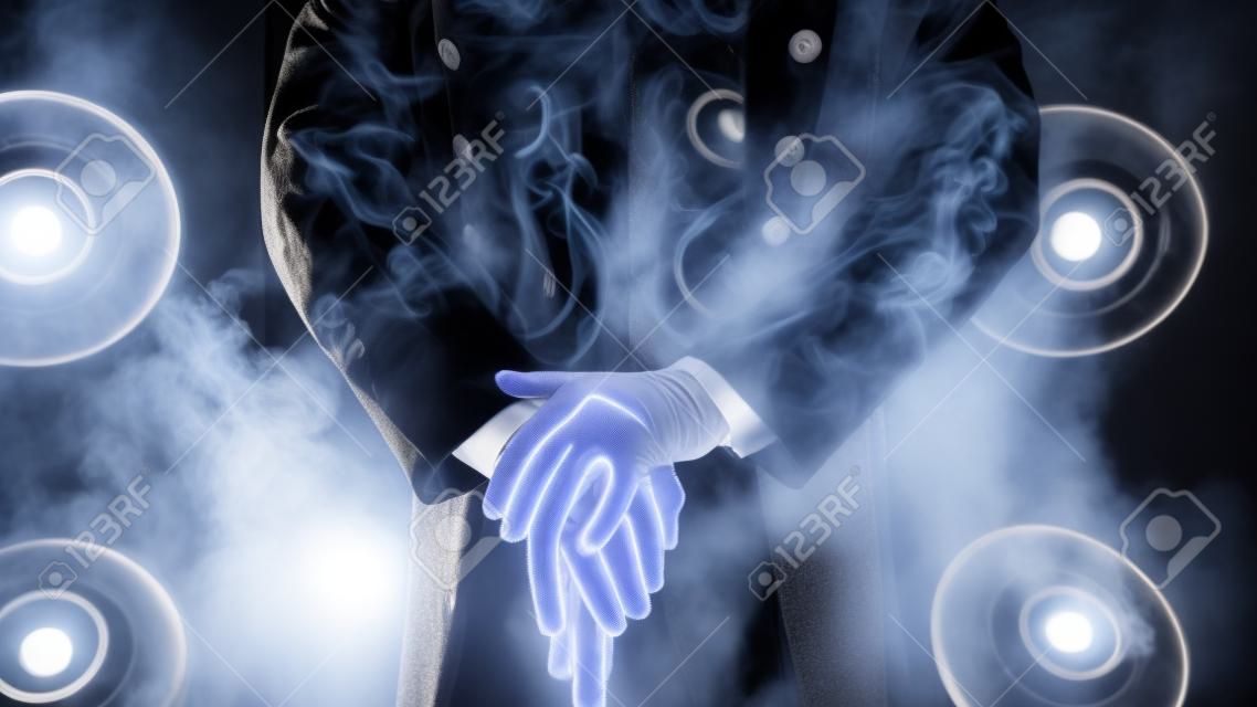 Showman. Pose, hands rest on stick. White gloves and beautiful sleeve of his coat, smoke on background of the spotlight