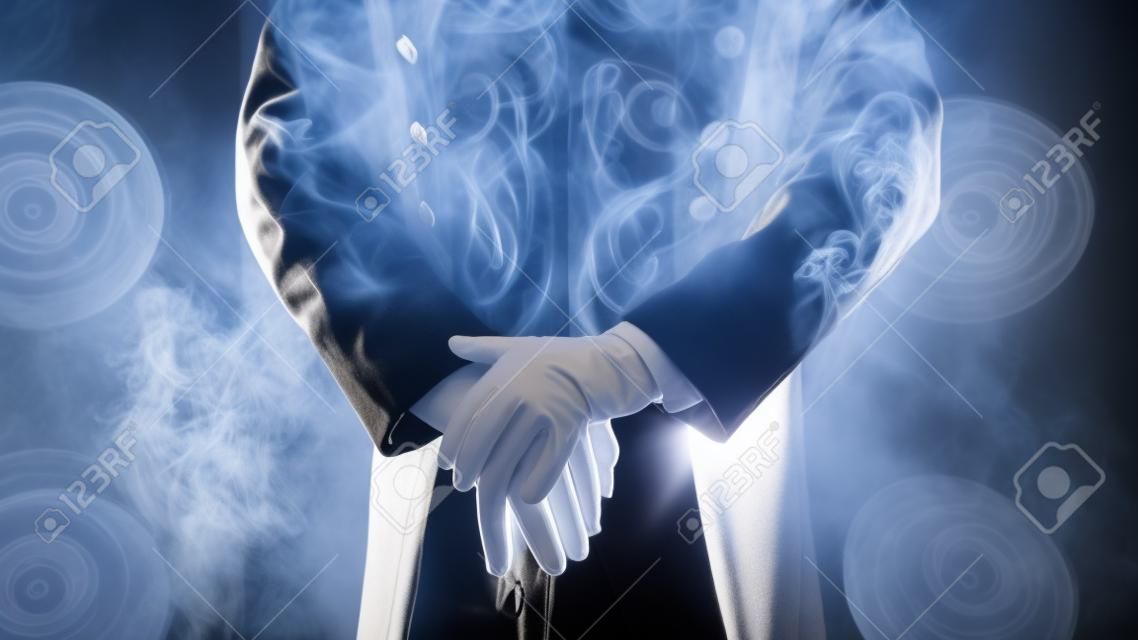 Showman. posa, mani appoggiate sul bastone. guanti bianchi e bella manica del cappotto, fumo sullo sfondo dei riflettori