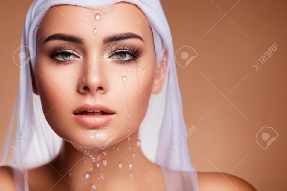 Clean skin, drops and trickles of water on the face. Young beautiful woman, close-up portrait