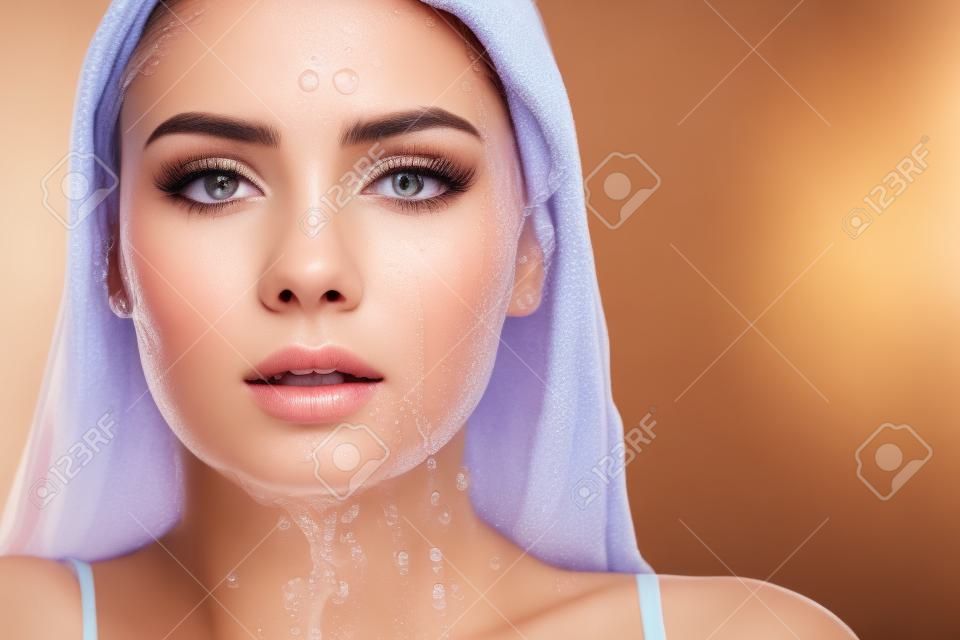 Clean skin, drops and trickles of water on the face. Young beautiful woman, close-up portrait