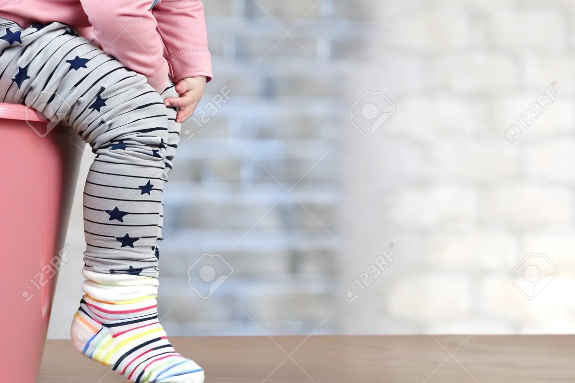 les jambes de l'enfant qui pend à partir d'un pot de chambre sur un fond bleu