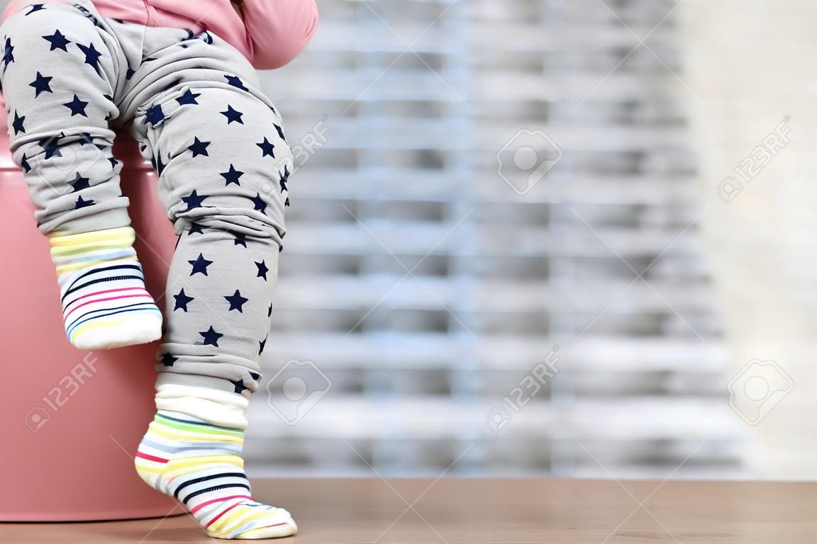 les jambes de l'enfant qui pend à partir d'un pot de chambre sur un fond bleu
