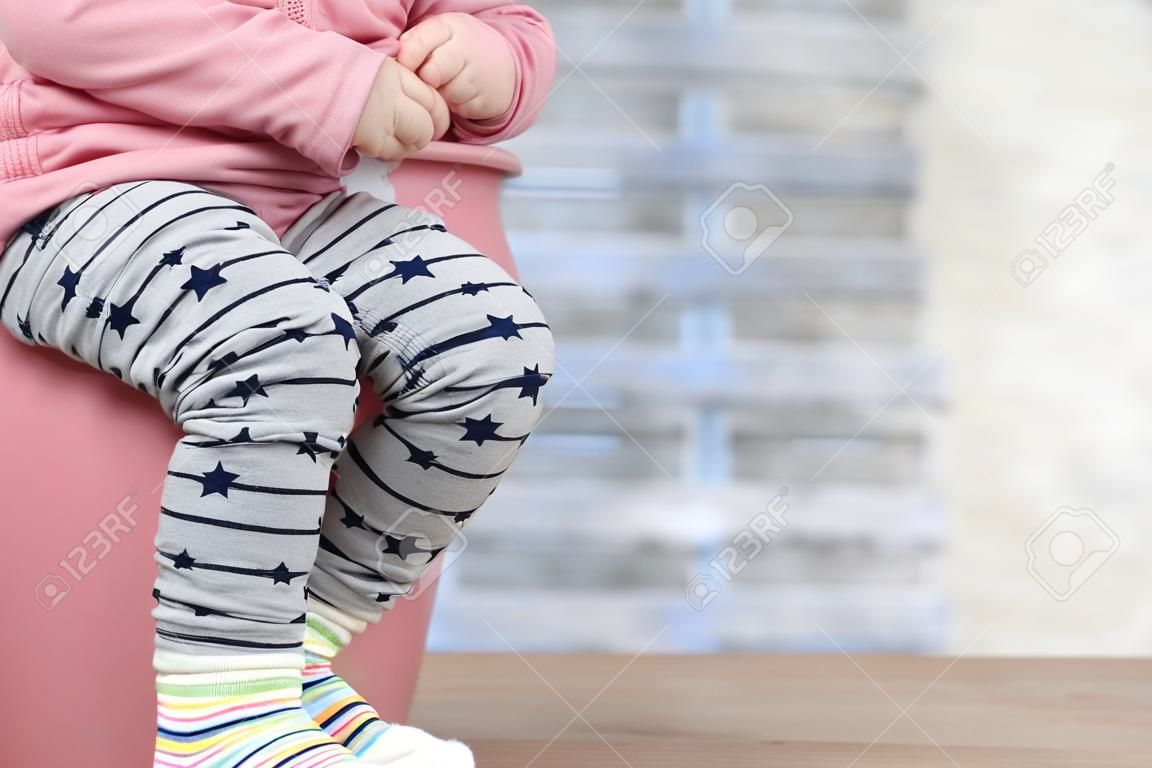 孩子的腿從尿壺垂下在藍色背景