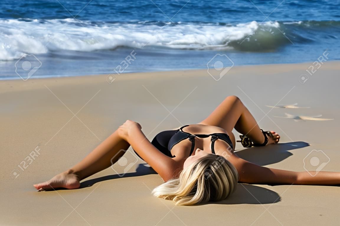 Attractive girl lying on the sand by the sea. Sunny day.