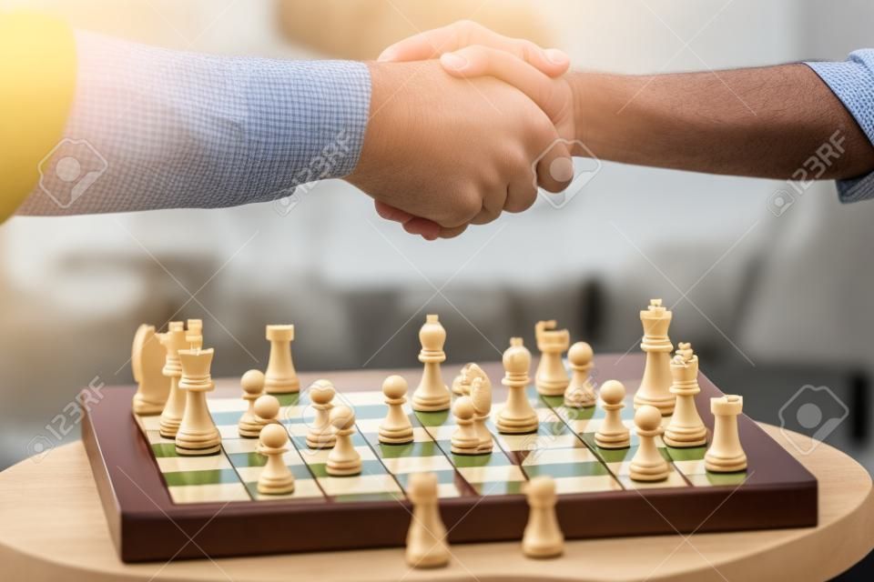 partial view of father and son shaking hands after playing chess board game
