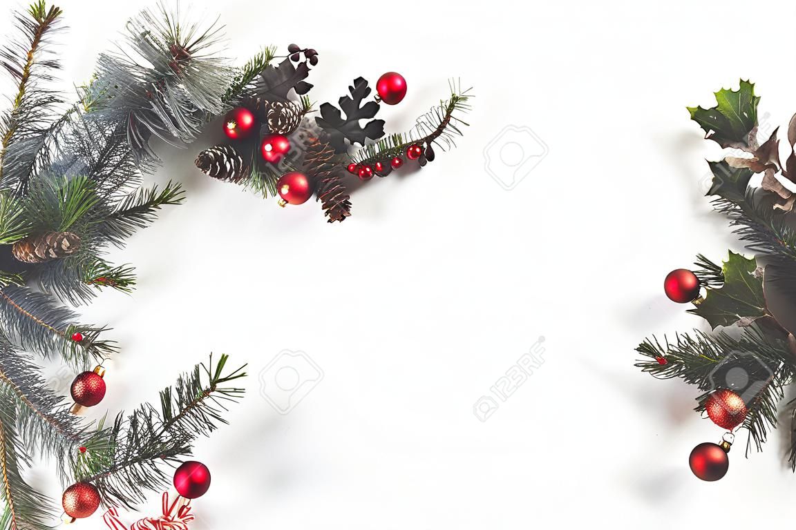 Widok z góry ramki świątecznej wykonanej z gałęzi jodłowych, bombek i szyszek sosnowych, izolowane na białym