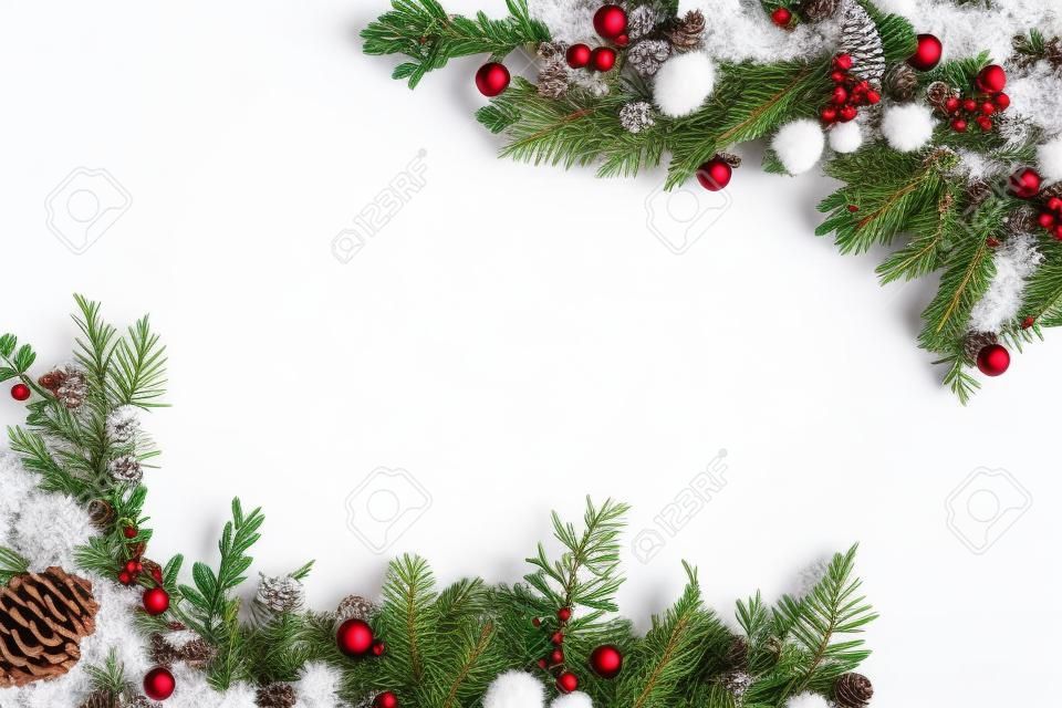 widok z góry świątecznej ramki wykonanej z gałęzi jodłowych, bombek i szyszek sosnowych, na białym tle