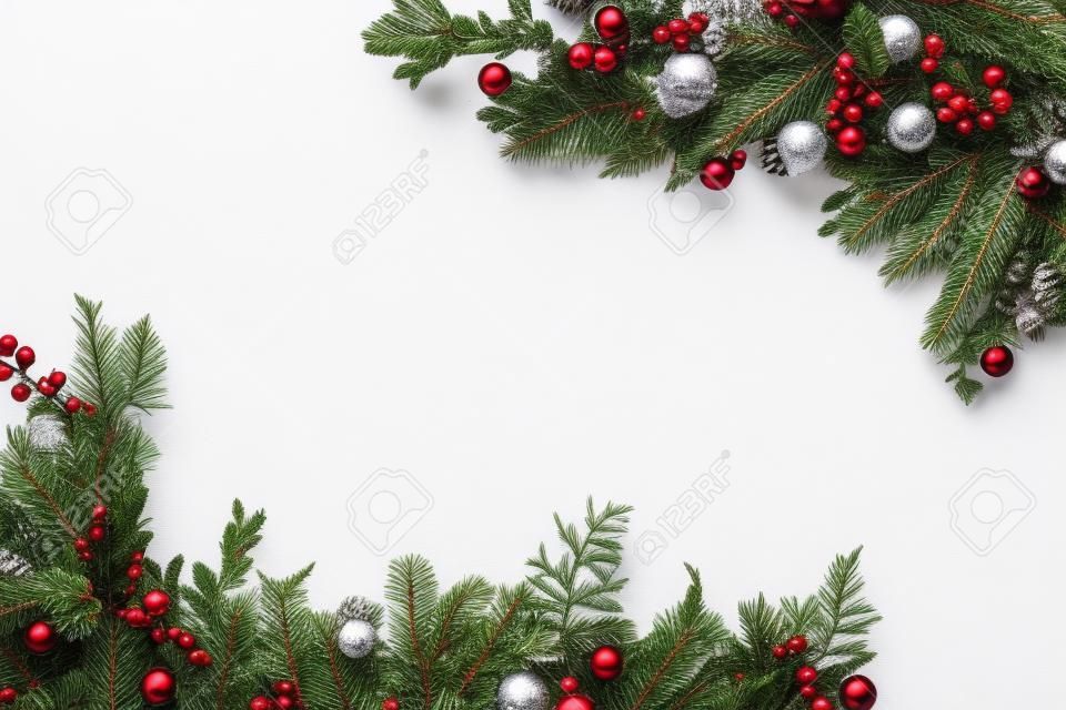 widok z góry świątecznej ramki wykonanej z gałęzi jodłowych, bombek i szyszek sosnowych, na białym tle