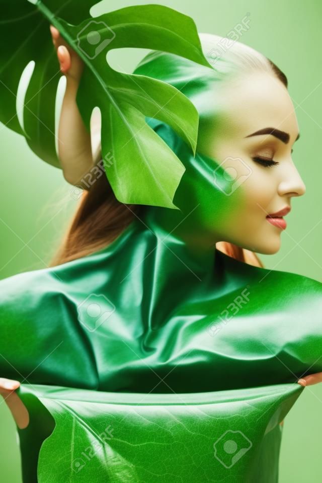 Attraktive Frau posiert mit tropischen Blatt
