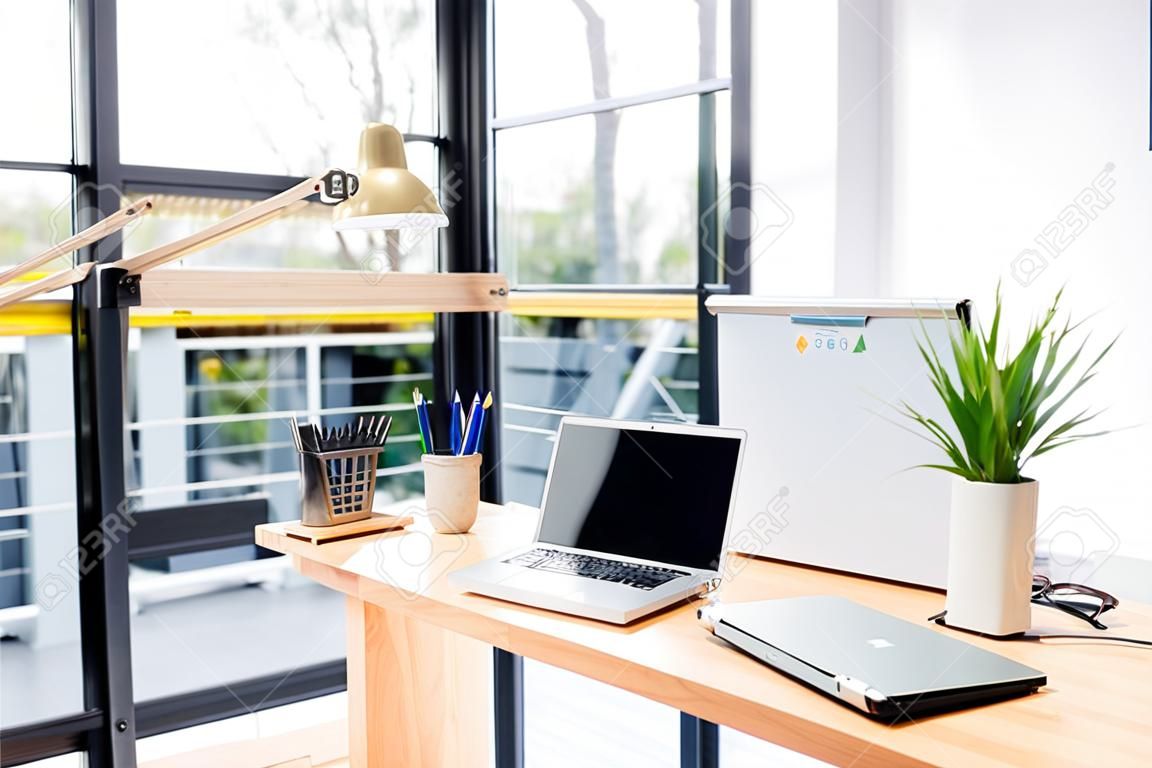 Modern kantoor met laptop en briefpapier geplaatst op houten bureau