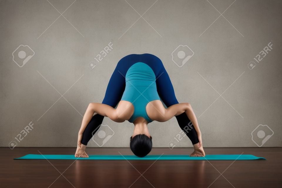 woman practicing yoga doing standing straddle forward bend pose, Prasarita Padottanasana