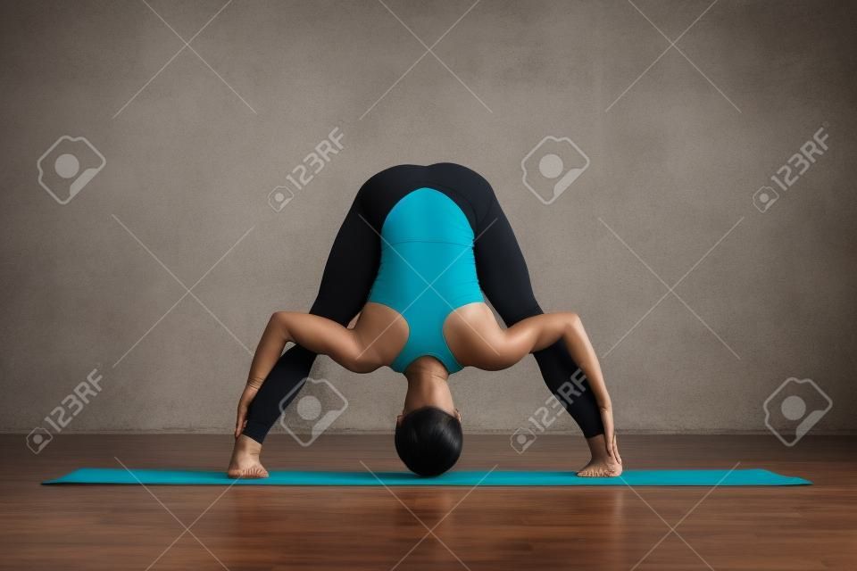 woman practicing yoga doing standing straddle forward bend pose, Prasarita Padottanasana