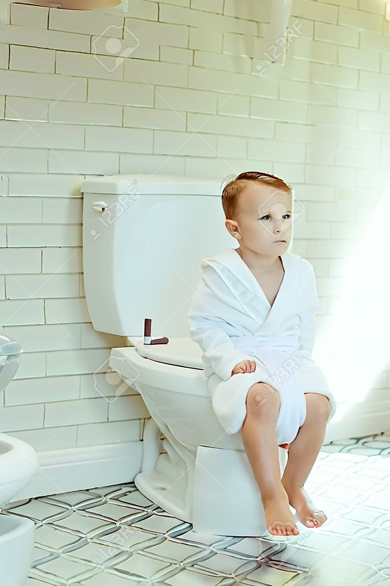 mignon petit garçon en sous-vêtements blancs assis sur les toilettes et à la recherche de suite