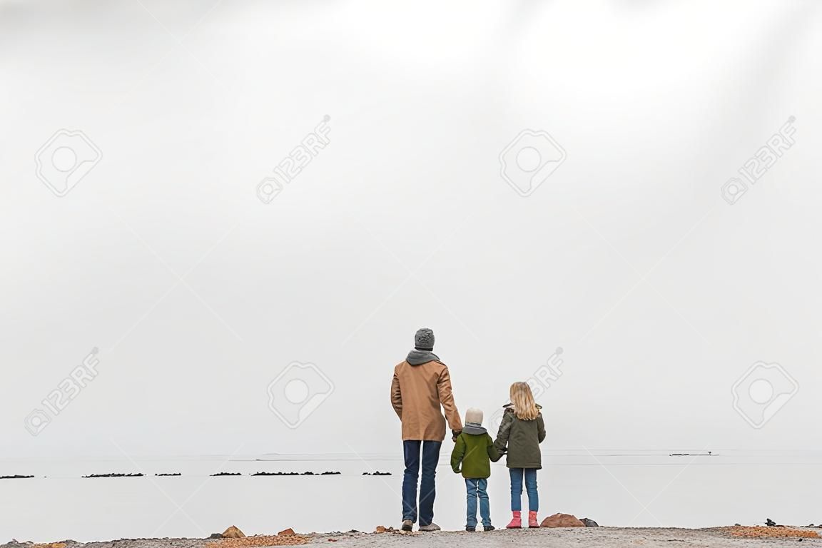 famille tenant la main et regardant la mer le jour d'automne nuageux