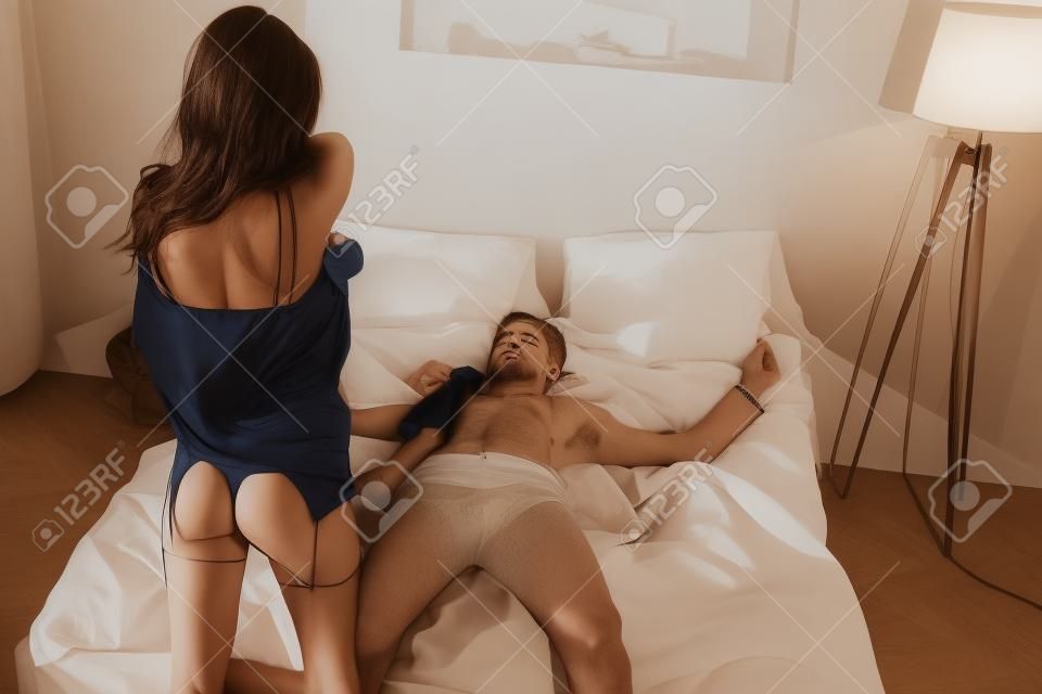 女人脫下衣服，而她的男朋友躺在床上蒙住眼睛
