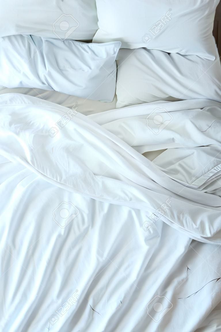 ベッドの上に白い寝具、枕、毛布が付いています