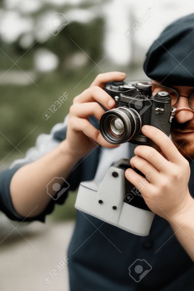 close-up shot of handsome adult man with vintage film camera outdoors