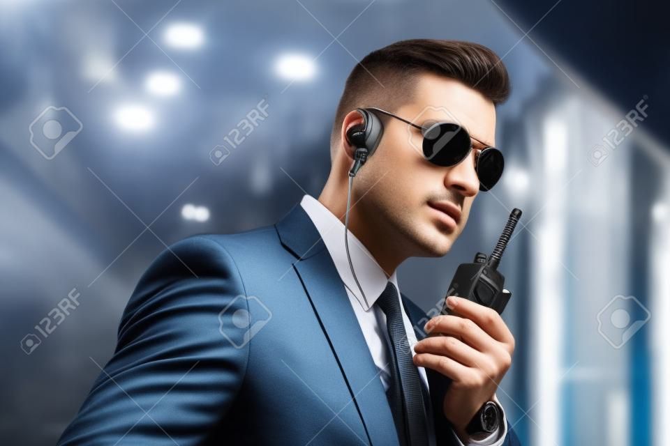 serious handsome security guard talking by portable radio