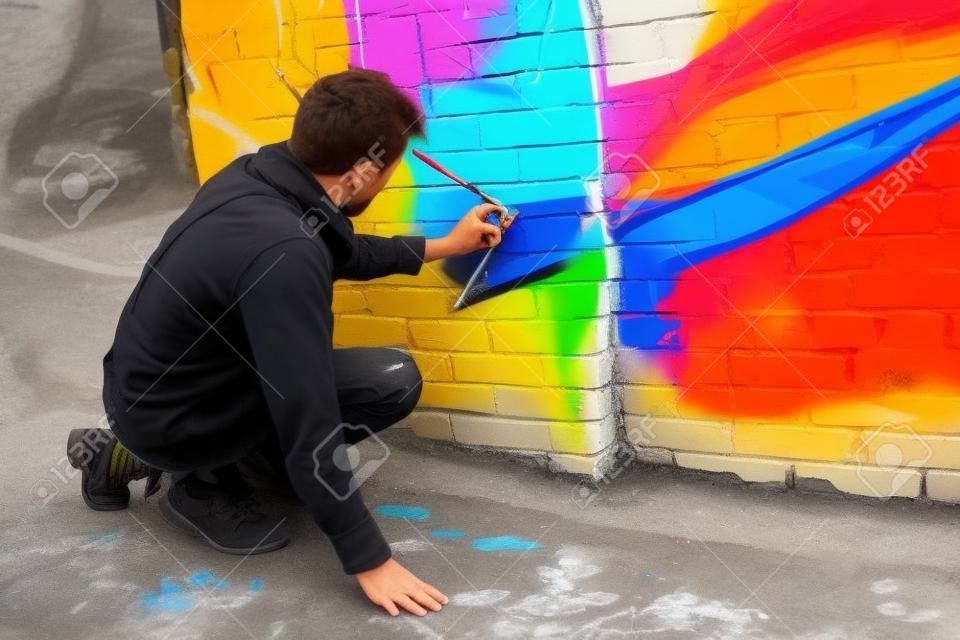建物の壁にカラフルな落書きを描くストリートアーティスト
