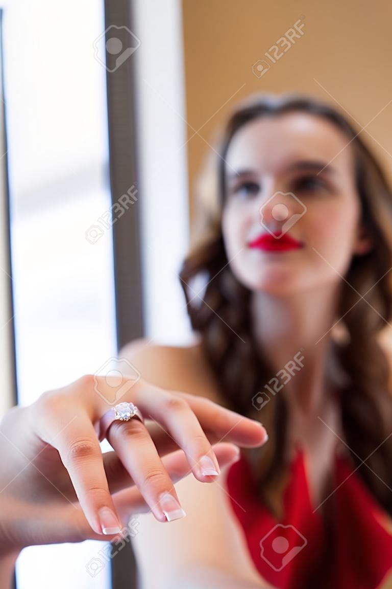 selective focus of man holding fiances hand with wedding ring on finger