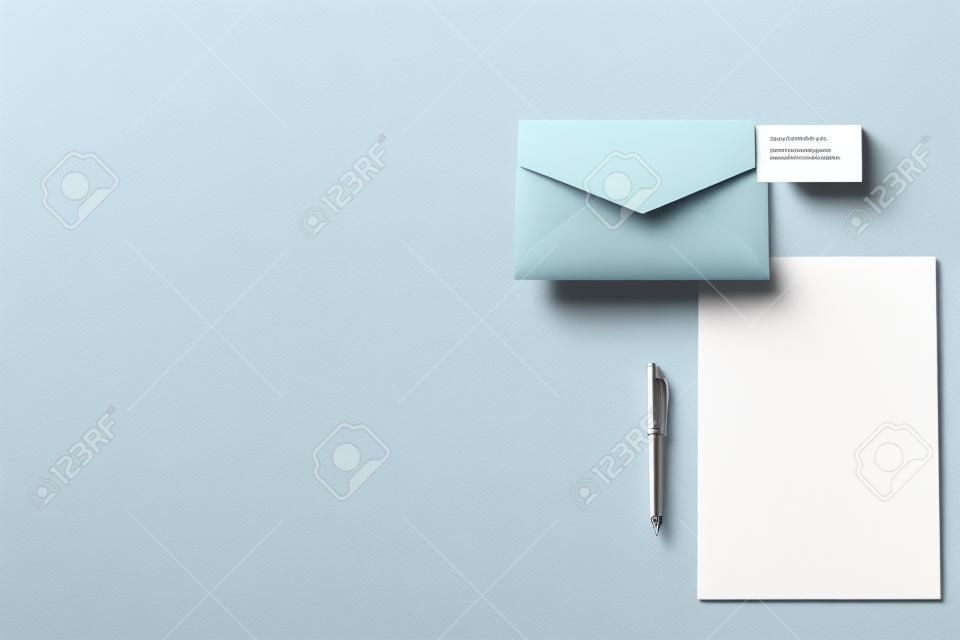 Widok z góry warstwowej koperty z pustym papierem i wizytówką na białej powierzchni do makiety