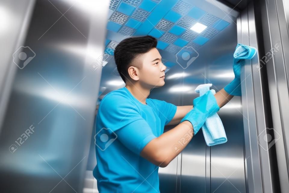 low angle view of handsome young cleaner washing elevator with rag and detergent