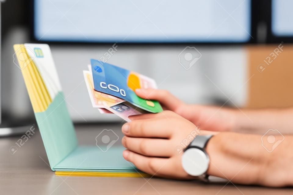 partial view of person holding credit card and euro banknotes at workplace