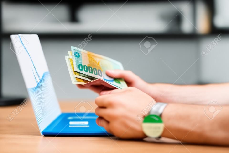 partial view of person holding credit card and euro banknotes at workplace